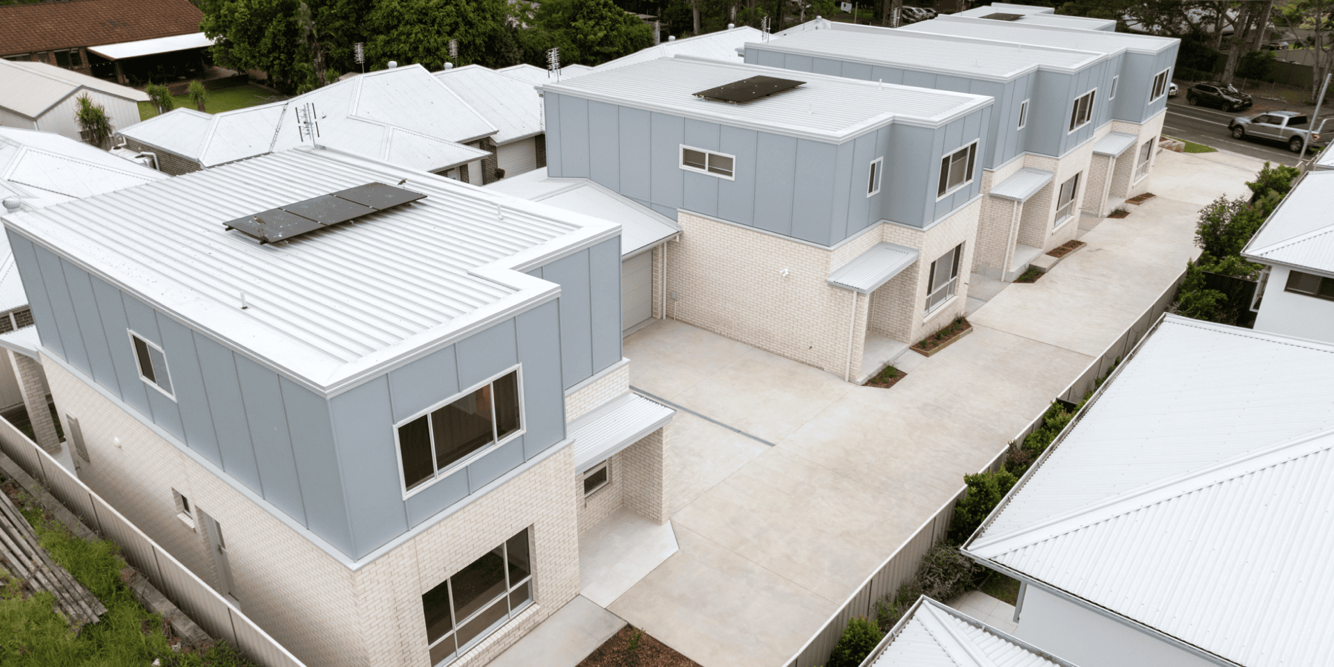 Aerial view of a multi-dwelling development with several two-storey homes and shared driveway.